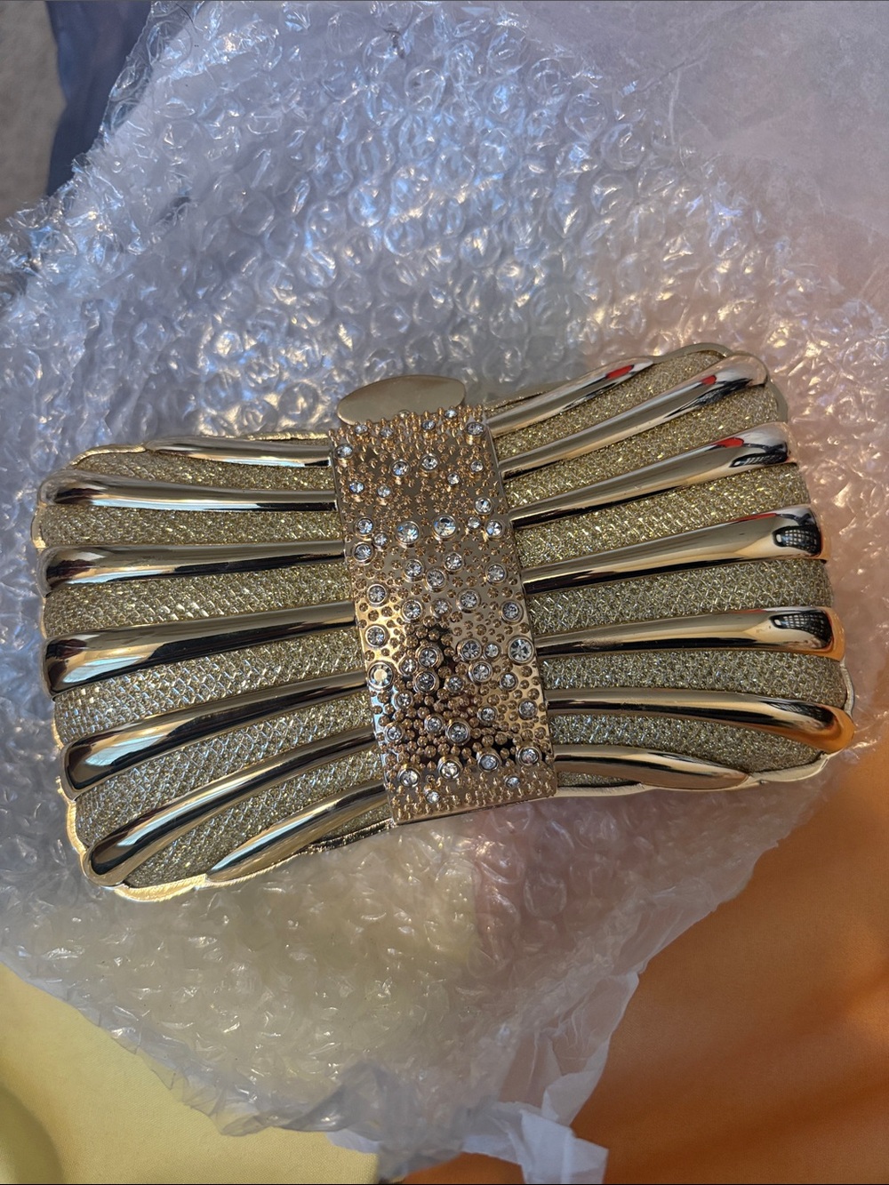 Metal alloy evening clutch with crystal embellishments, gold-tone finish.